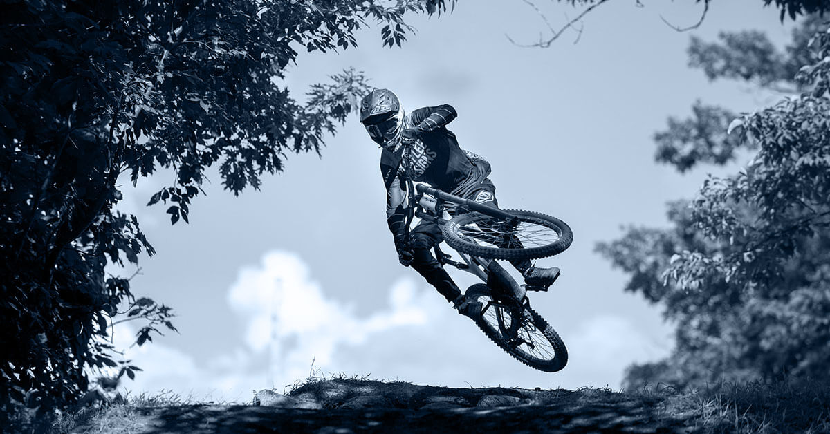 Mountainbiker beim Sprung über Kuppe